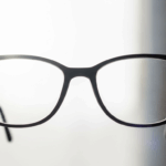 A person holding up a pair of spotlessly clean eyeglasses to the light, showing off the sparkling, clear lenses.