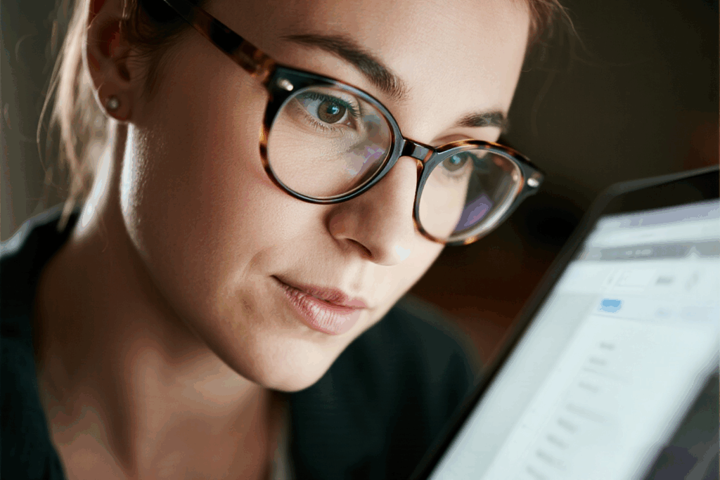 a person wearing stylish glasses, looking at a laptop screen
